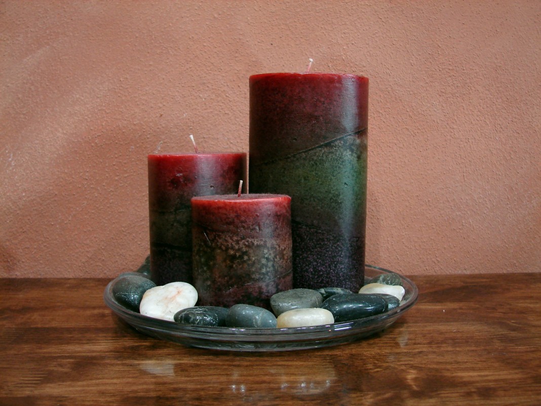 tres velas en un plato con piedras